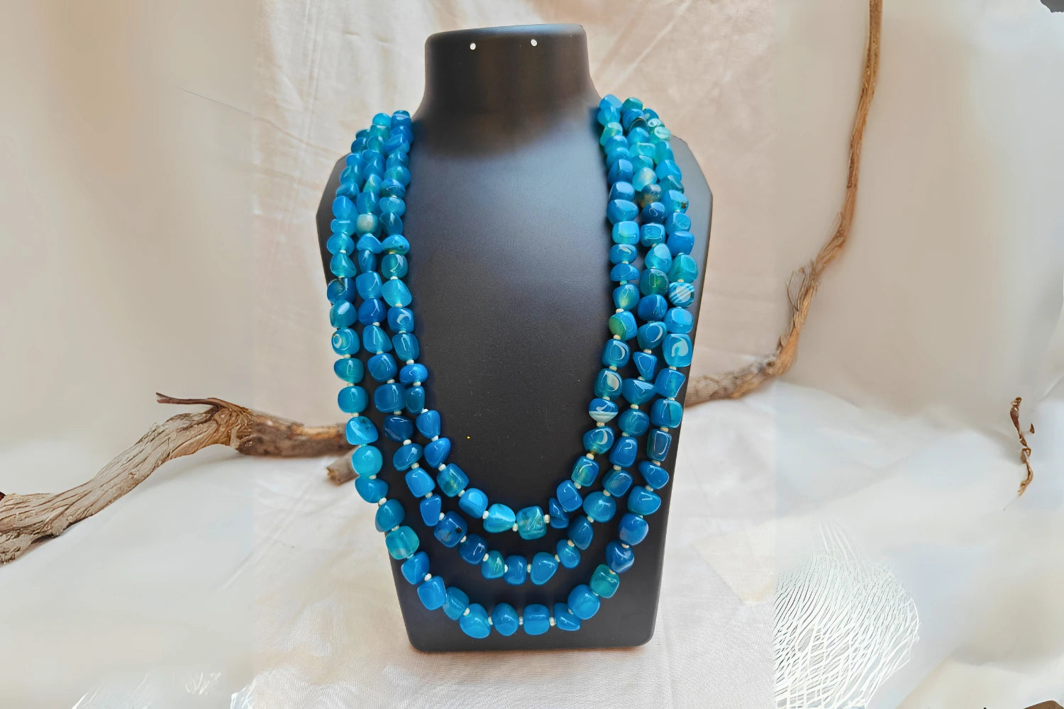 Bead Mala made of aquamarine stones in light blue, multi-layered jewelry displayed on a black stand.