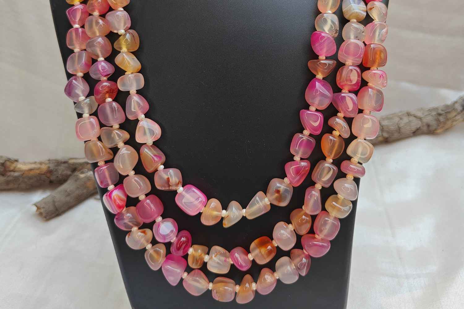 Bead Mala made from light pink rose quartz stones for love and harmony, displayed elegantly on a black stand.